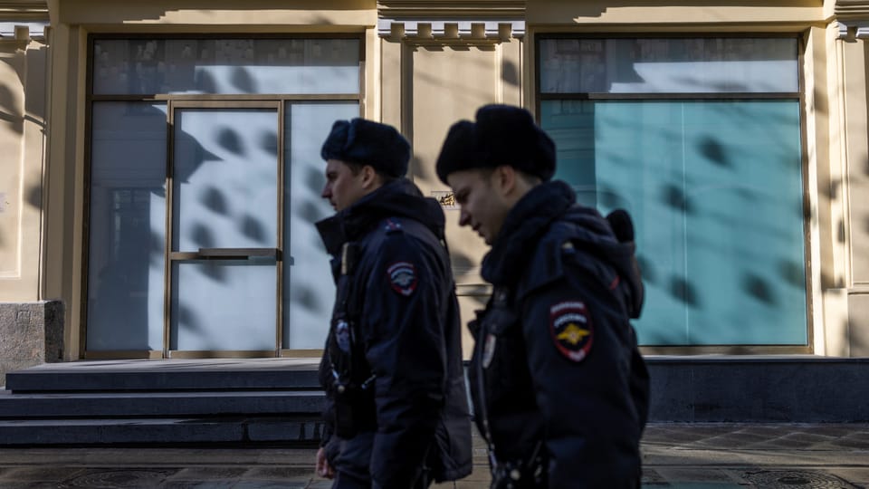 Two police officers walk past a boutique in Russia.