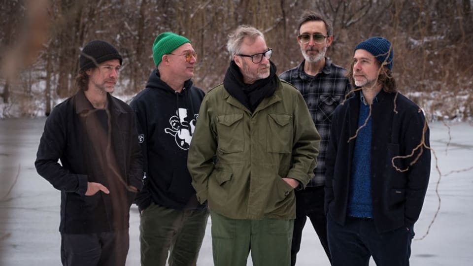 Five middle-aged men stand in the snowy park