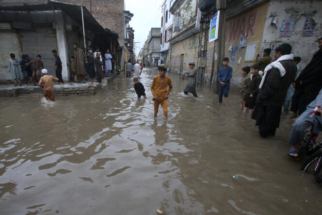 Young people wade through a street flooded by heavy rains in Peshawar, Pakistan, Monday April 15, 2024. 