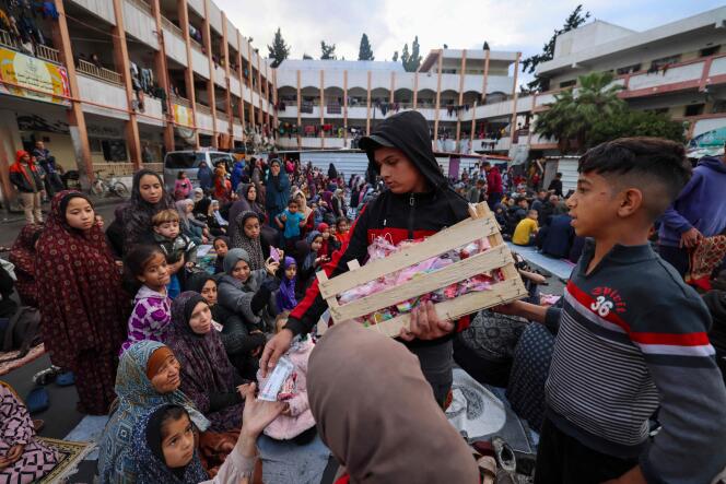 A boy distributes sweets to displaced Palestinians as they attend a special morning prayer to start the Eid-ul-Fitr holiday, marking the end of the holy month of Ramadan, at a school-turned-shelter in Rafah, southern Gaza Strip, April 10, 2024.